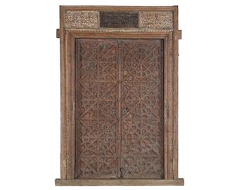 May include: A rectangular wooden door frame featuring double doors with intricate geometric star patterns carved into the wood. The top section includes three carved panels with floral motifs and a central dark rectangular inset panel.