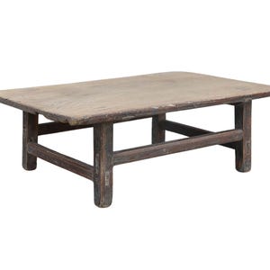 May include: A low rectangular coffee table constructed from weathered brown wood. The table features a smooth, flat top surface with visible grain patterns and is supported by four sturdy legs connected by horizontal stretchers on all four sides.