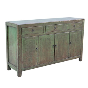 May include: A distressed green wooden cabinet with three drawers and four doors. The cabinet has a rectangular shape and is painted in a faded green color. The hardware is dark metal. The cabinet is a piece of furniture.