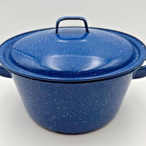 Peut inclure: Une marmite en émail bleu profond avec un couvercle assorti, présentant un motif moucheté blanc sur tout l'extérieur. La marmite comprend deux poignées latérales et une poignée arquée sur le couvercle, avec une forme arrondie classique.
