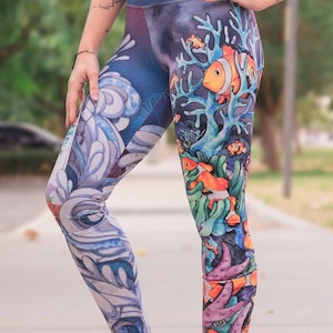 May include: A pair of blue, purple, and orange leggings with a colorful underwater scene featuring fish and coral. The leggings are high-waisted and have a stretchy fabric.