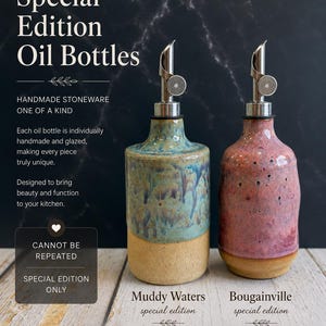 Puede incluir: Dos botellas de aceite de gres hechas a mano con vertedores de metal. La botella de la izquierda presenta un esmalte azul y verde sobre una base color canela, etiquetada como Muddy Waters. La derecha tiene un esmalte rosa y morado sobre una base color canela, etiquetada como Bougainville.