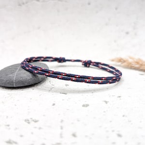 Op de afbeelding: Een gevlochten armband in marineblauw en rood met een eenvoudige knoop sluiting.