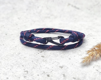 Può includere: Un braccialetto in paracord blu navy e rosso con una chiusura in metallo nero.