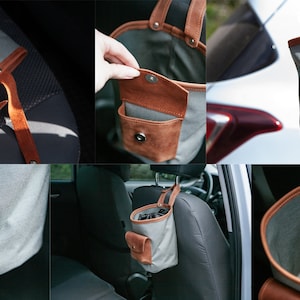 Op de afbeelding: Een grijze canvas tas met een bruin leren zakje en handvat. De tas hangt aan de hoofdsteun van een autostoel.