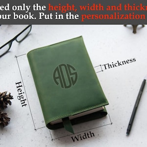May include: A green leather-bound journal with a monogrammed initial "ADS" on the front cover. The journal is closed and the dimensions are labeled: height, width, and thickness.