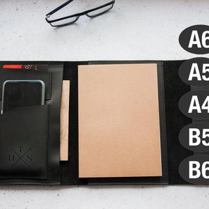 May include: Black leather portfolio with a phone pocket, a notepad, and a pen holder. The portfolio is open and the notepad is visible. The portfolio is labelled with the letters "A6", "A5", "A4", "B5", and "B6".