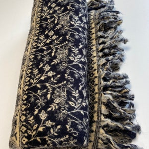 Puede incluir: Bufanda enrollada azul marino con un estampado floral crema y bordes con flecos. La bufanda presenta un dise&ntilde;o bot&aacute;nico detallado a lo largo de los bordes y en toda la tela. Los bordes con flecos a&ntilde;aden un toque decorativo a este accesorio.