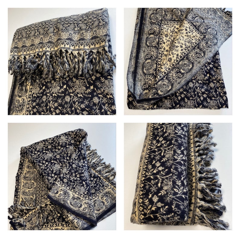 Puede incluir: Un chal de color azul marino y crema con un estampado floral y flecos. El chal est&aacute; doblado y drapeado, mostrando el intrincado dise&ntilde;o y la textura. Los flecos a&ntilde;aden un elemento decorativo a los bordes del chal.