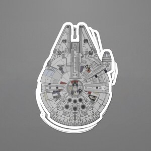 May include: A sticker depicting the Millennium Falcon starship, with a detailed illustration. The design shows the ship's distinctive circular form, with intricate mechanical details in shades of grey, white, and red. The sticker has a white border and is set against a grey background.