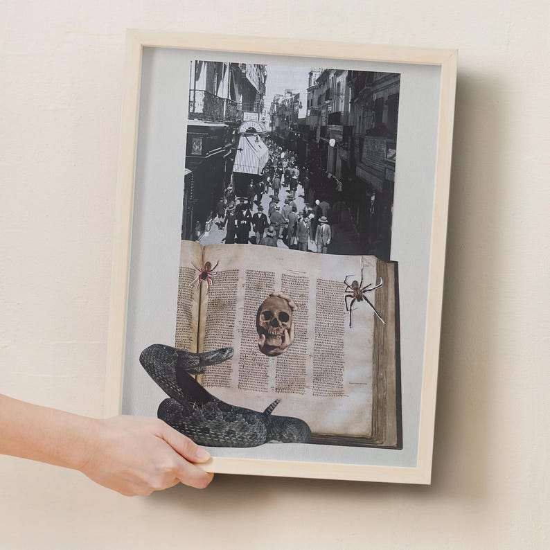 May include: Framed artwork featuring a black and white street scene above a collage of a vintage book, skull, snake, and spiders. The artwork is in a light wood frame.