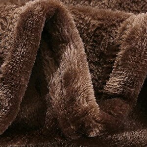 May include: Close-up of a brown plush fabric with a soft, fuzzy texture. The fabric is folded in a way that shows the depth and texture of the material.