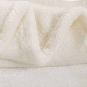 May include: A close-up of a white plush blanket folded to show its soft, fluffy texture.