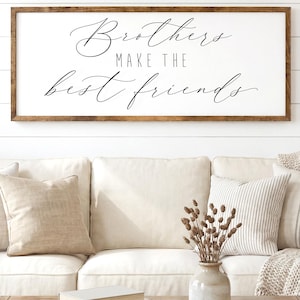 May include: A framed wooden sign with the text "Brothers make the best friends" in elegant script. The sign hangs above a cream-colored sofa with decorative pillows. The bottom of the image reads "FULLY CUSTOMIZABLE - SIZES, COLORS".