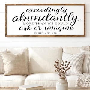 May include: A framed wooden sign with the text "exceedingly abundantly more than we could ask or imagine" in black script. The sign is displayed above a white sofa with beige pillows. The text "FULLY CUSTOMIZABLE - SIZES, COLORS" is at the bottom.