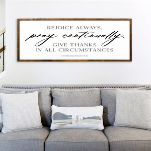 May include: A framed wood sign with a white background and black text that reads "Rejoice always, pray continually, give thanks in all circumstances 1 Thessalonians 5:18".