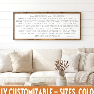 May include: A framed wooden sign with a quote in black text, displayed above a white sofa with beige pillows. The sign reads, "I am the richest man in America." The bottom of the image has the text "FULLY CUSTOMIZABLE - SIZES, COLORS."