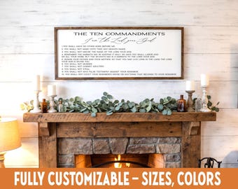 May include: A framed wooden sign displays "The Ten Commandments" in black text. The sign is above a fireplace with candles, bottles, and greenery. The bottom of the image has the text "FULLY CUSTOMIZABLE - SIZES, COLORS".