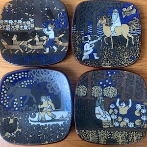 Peut inclure: Quatre assiettes carrées décoratives avec des fonds bleu foncé et marron. Chaque assiette présente une illustration unique de personnages et d'animaux dans un cadre forestier. Les assiettes ont une esthétique vintage, avec l'année 1982 ou 1978 imprimée sur certaines.