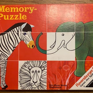 May include: A vintage Ravensburger Memory-Puzzle game box with a red background and colourful illustrations of a zebra, elephant, lion, and flowers. The box features the text "Memory-Puzzle" and "Ravensburger Spiele".