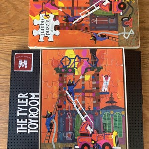 May include: A vintage cardboard box containing a 35-piece jumbo puzzle depicting a fire engine responding to a fire in a building. The puzzle pieces are colourful and feature a red fire engine, a ladder, and firemen.