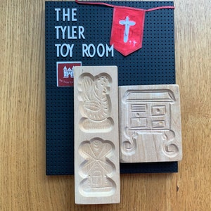 May include: Two wooden cookie cutters, one shaped like a house and the other with a bird design. The cutters are on a black pegboard with the words "The Tyler Toy Room" in white letters.