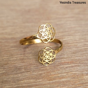 May include: Gold-toned adjustable ring with two openwork flower designs. The ring is made of metal and features a geometric pattern.