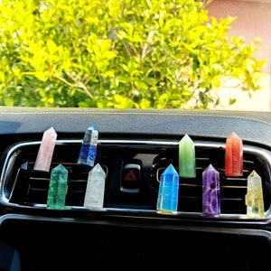 Peut inclure: Un ensemble de dix diffuseurs d'air de voiture en cristal coloré. Les cristaux sont disposés en rangée sur une bouche d'aération du tableau de bord d'une voiture. Les cristaux sont dans les couleurs de l'arc-en-ciel, avec un cristal transparent au milieu.