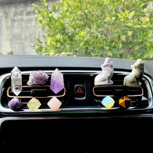 Può includere: Una collezione di profumatori per auto in cristallo, tra cui una punta di quarzo trasparente, punte di ametista, una punta di quarzo rosa, una punta di cristallo trasparente, una punta di cristallo verde, una punta di cristallo blu, una punta di occhio di tigre e due figurine di animali in cristallo.