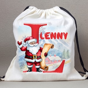 May include: White canvas drawstring bag featuring a red and white Santa Claus illustration and the letter "L" in red. The bag is personalised with the name "Lenny" printed in red.