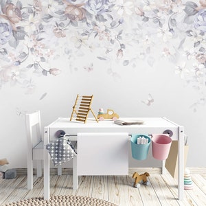 May include: A white children's table and chairs set with a floral wallpaper backdrop. The table has two hanging storage baskets, one blue and one pink. There are toys on the floor and a wooden abacus on the table.