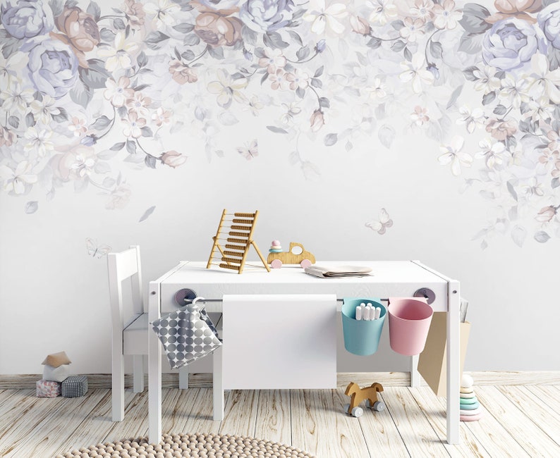 May include: A white children's table and chairs set with a floral wallpaper backdrop. The table has two hanging storage baskets, one blue and one pink. There are toys on the floor and a wooden abacus on the table.