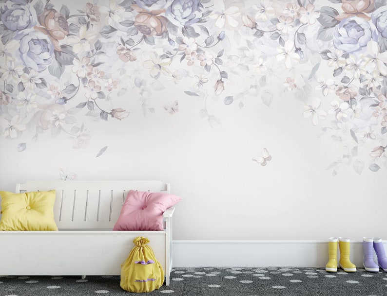 May include: A white bench with a yellow and pink cushion on it. The bench is in front of a wall with a floral wallpaper design. The wallpaper features a light purple and white floral pattern with butterflies.