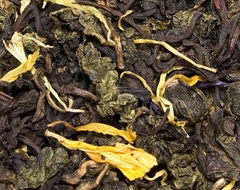 May include: Close-up of a blend of loose leaf tea with green and black tea leaves and dried yellow fruit pieces.