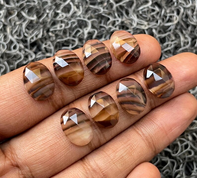 May include: Eight faceted oval-shaped brown and white agate gemstones with a striped pattern.