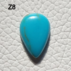 May include: A teardrop-shaped turquoise gemstone with a blue-green color and brown veins. The stone is set against a white background.