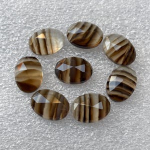 May include: Eight oval-shaped, faceted, brown and white striped agate gemstones.