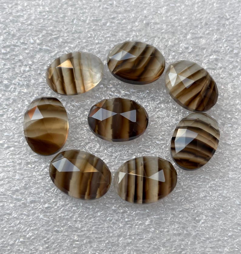 May include: Eight oval-shaped, faceted, brown and white striped agate gemstones.
