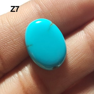 May include: A bright turquoise oval cabochon gemstone with brown veins. The stone is approximately 1 inch long and 0.75 inches wide.