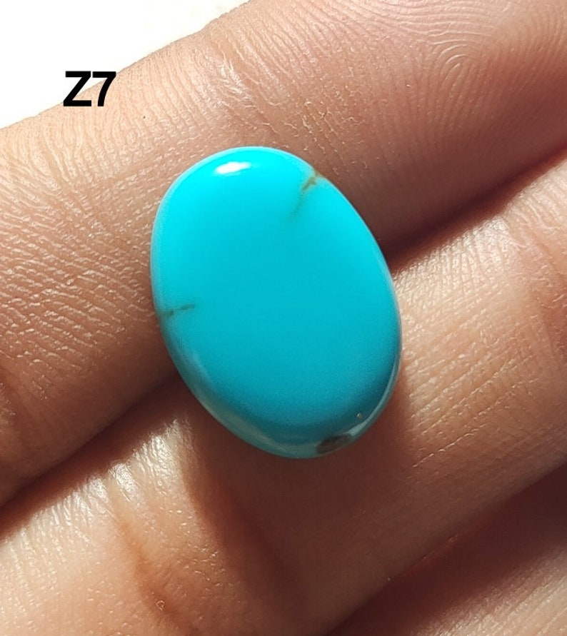 May include: A bright turquoise oval cabochon gemstone with brown veins. The stone is approximately 1 inch long and 0.75 inches wide.