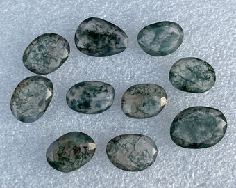 May include: Ten green moss agate cabochons, each with a unique pattern of green and white moss-like inclusions. The cabochons are oval shaped and have a smooth, polished surface.