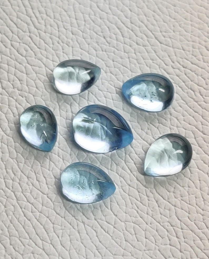 May include: Six teardrop-shaped, light blue gemstones with a translucent finish.