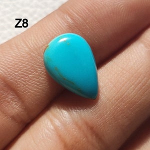 May include: A teardrop-shaped turquoise cabochon with a blue-green color and brown veins. The stone is approximately 1 inch long.