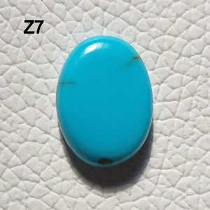 May include: A bright turquoise oval cabochon gemstone with dark brown veins. The stone is set against a white background. Z7.