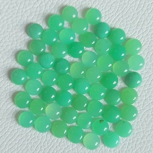 May include: A collection of round, green gemstone cabochons. The cabochons are smooth and polished, with a light green color.
