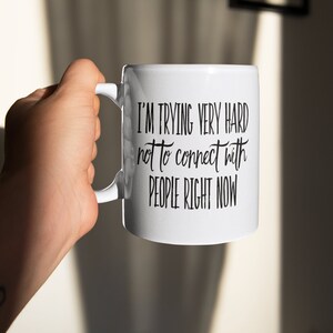 May include: White ceramic mug with black text that reads "I'm trying very hard not to connect with people right now".