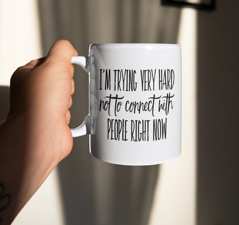 May include: White ceramic mug with black text that reads "I'm trying very hard not to connect with people right now".