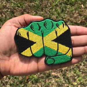 May include: A green, yellow, and black embroidered patch shaped like a fist with the Jamaican flag colors.