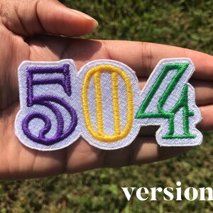 May include: Purple, yellow, and green embroidered patch with the numbers 504. The patch is on a white background.