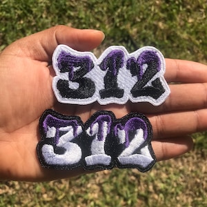 May include: Two embroidered iron-on patches with the number 312 in white with a black outline and purple dripping accents.